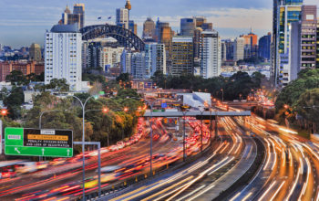 Long exposure blurred vehicle motion on multi-lane Warringah freeway going through North Sydney in Sydney, Australia. Headlights and backlights during rush hour commute towards Sydney harbour bridge and CBD towers.